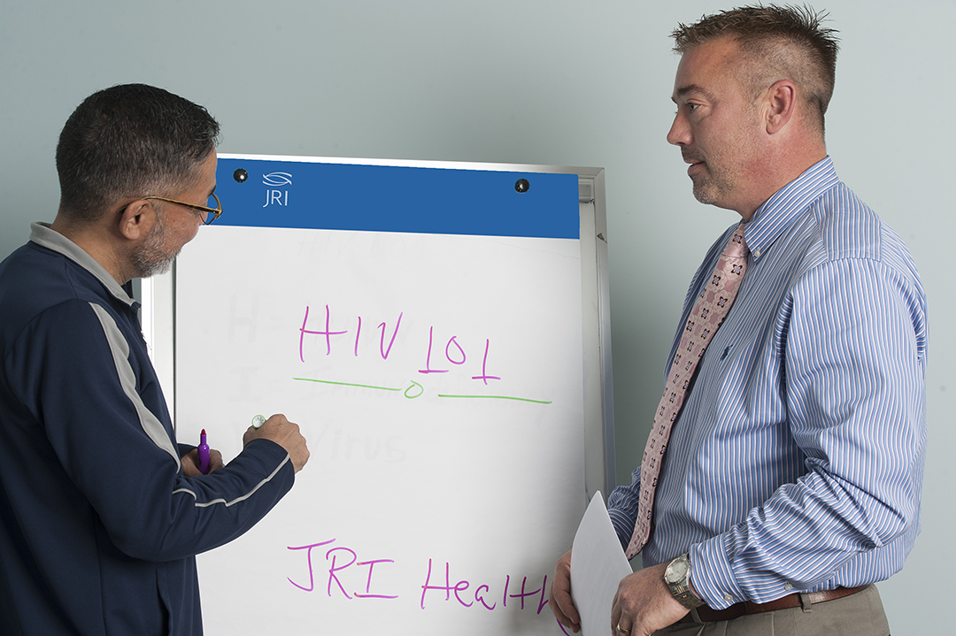 Two men with easel discussing HIV