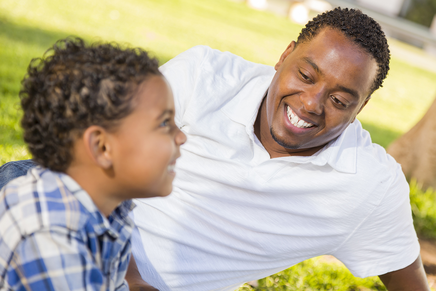 Black adult male lying in the grass with black child